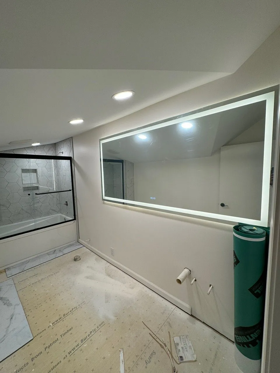 Bathroom with a large lighted LED mirror and recessed lights