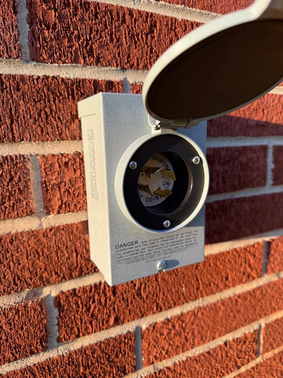 Outdoor generator power inlet box mounted on a brick wall