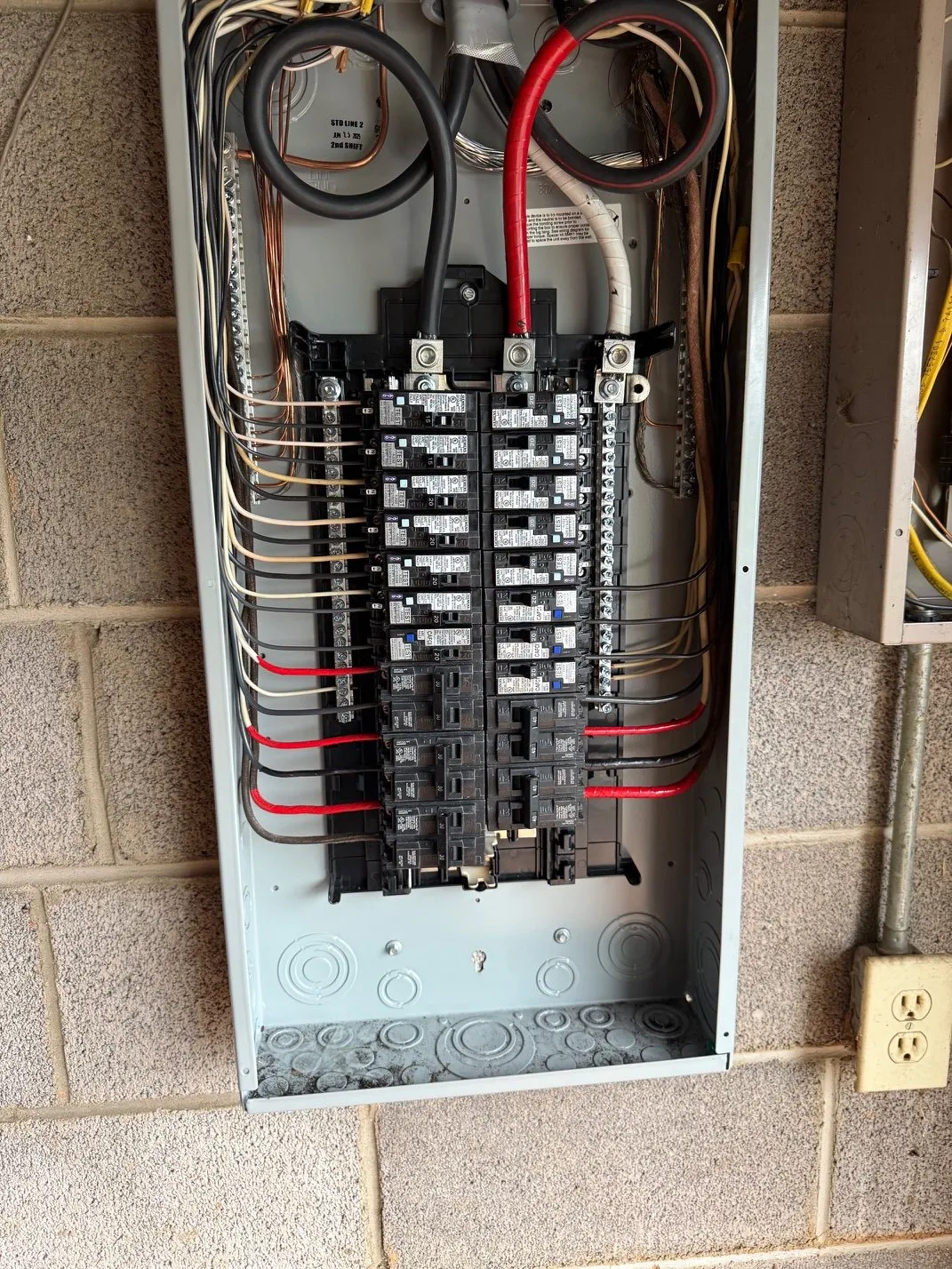 Breaker panel with neatly dressed wiring on a block wall