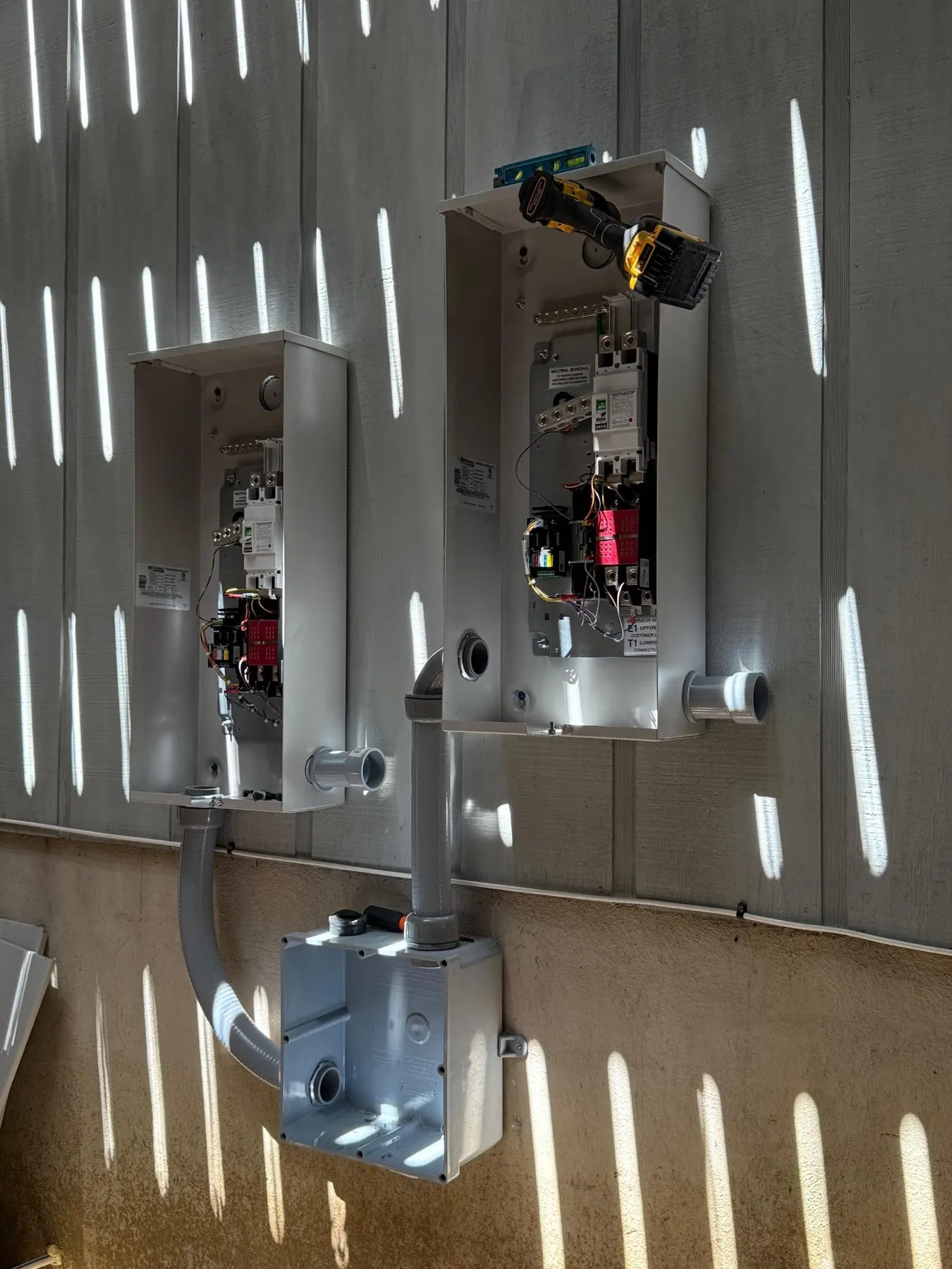 Two generator transfer switches being installed on an outside wall