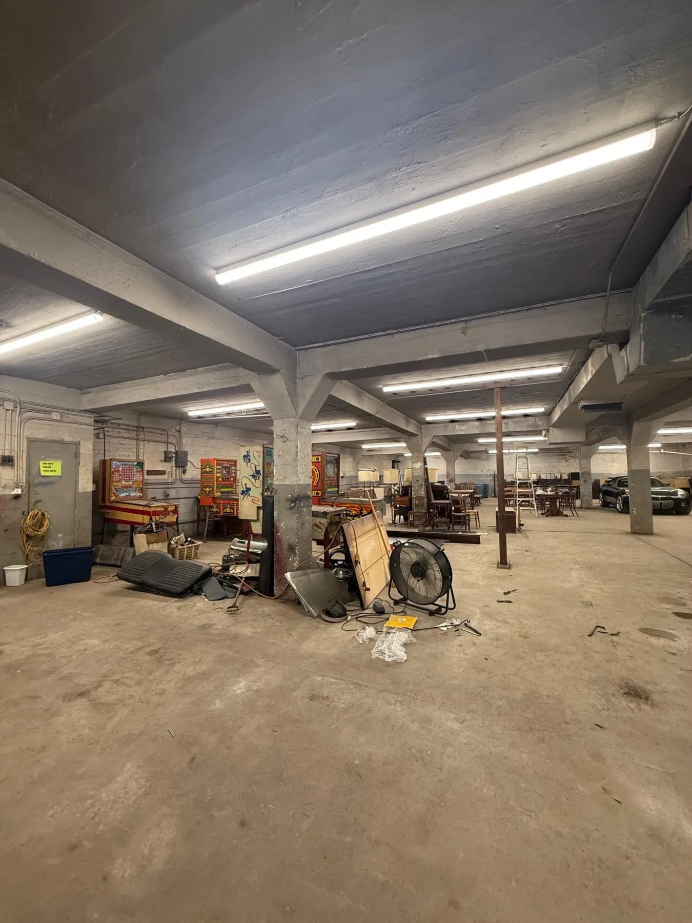 Large warehouse lit by long LED fixtures between concrete beams